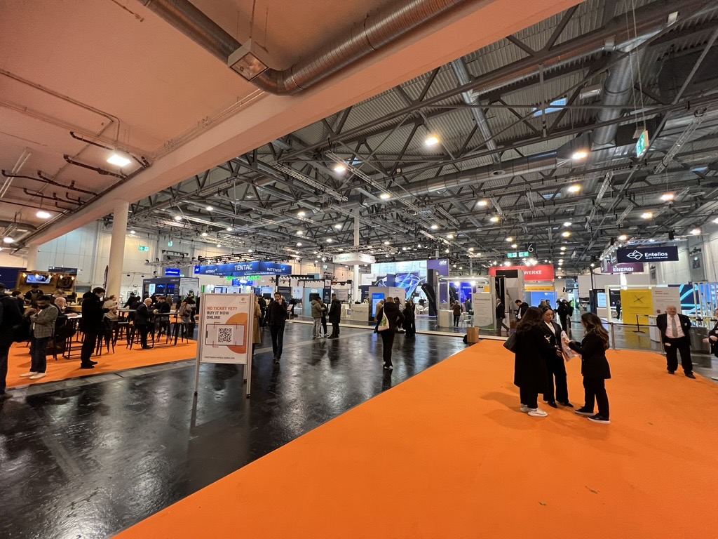 Bild der Messehalle mit Ausstellungsständen und Besuchern