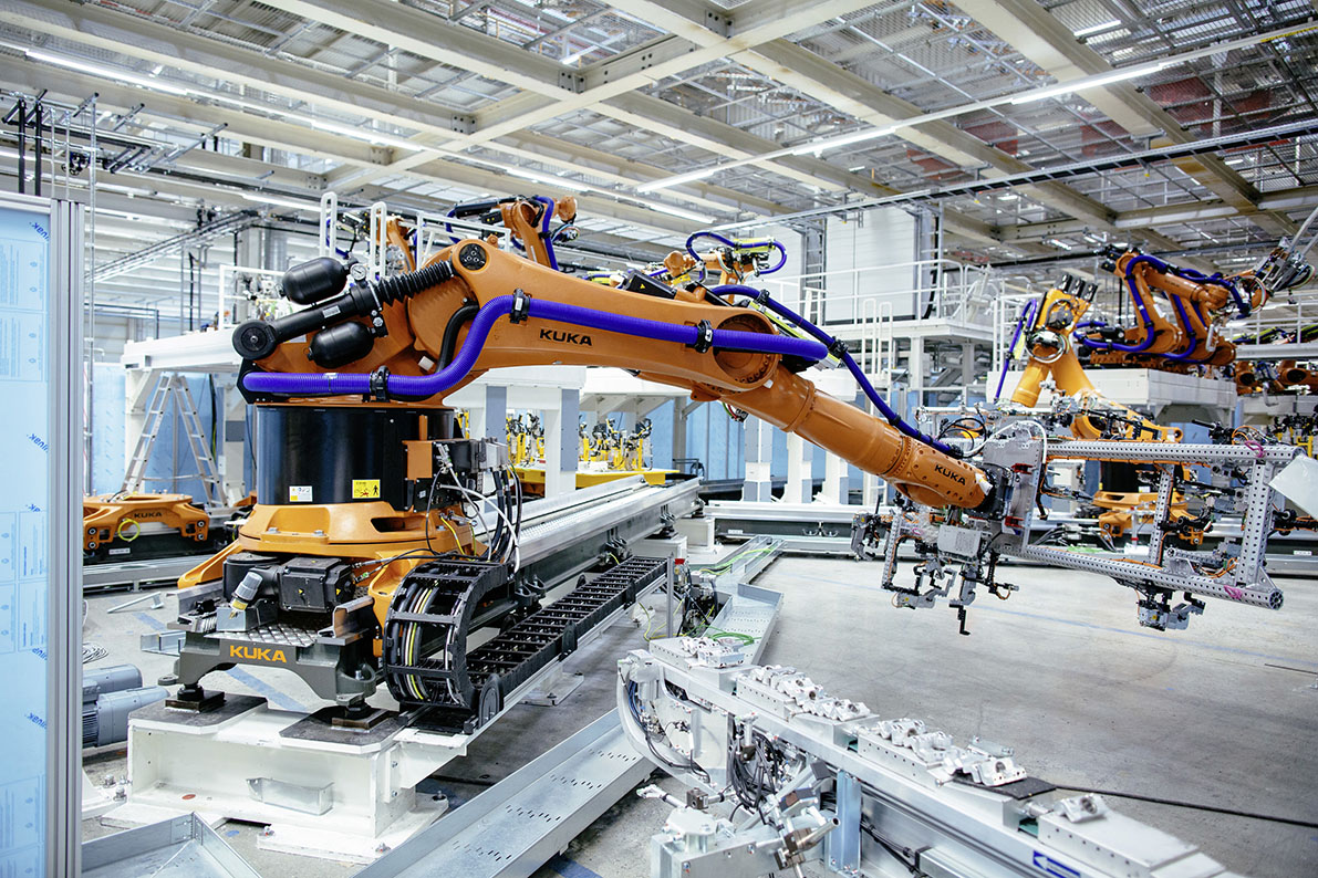 Automatisierte Fertigungsanlage im Maschinen- und Anlagenbau mit Industrierobotern von KUKA in einer modernen Produktionshalle – Beispiel für komplexe Industrieprojekte, digitale Projektmanagement-Software und Projektsteuerung in der Fertigungsindustrie.